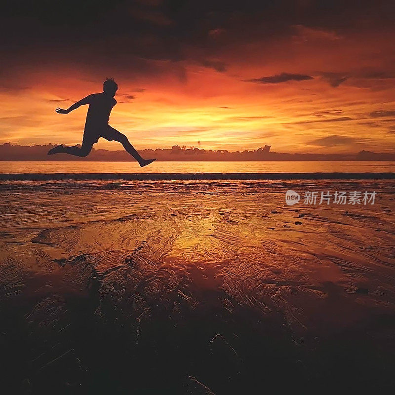 Silhouette of jumping man on sunrise or sunset  background. beautiful sand foreground at the beach in Asia, Thailand